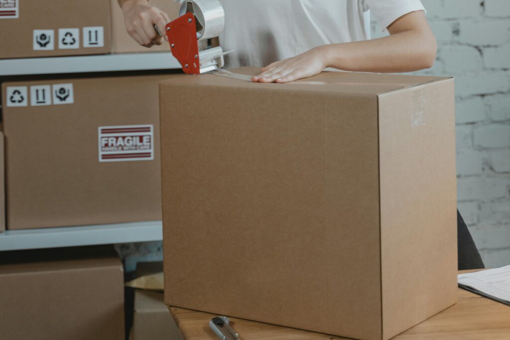 A cropped image of a professional mover sealing a carton